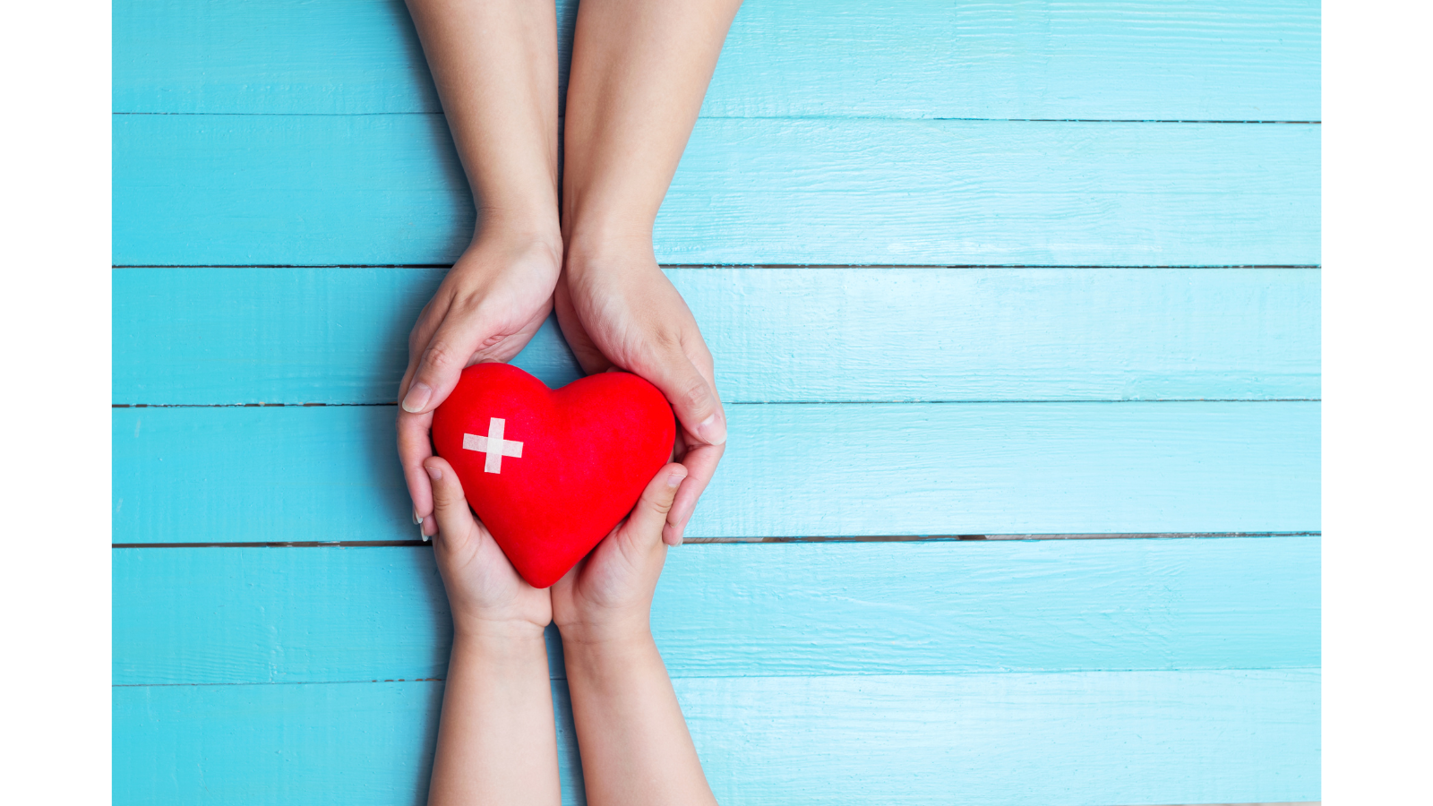four hands holding a red heart with a white cross